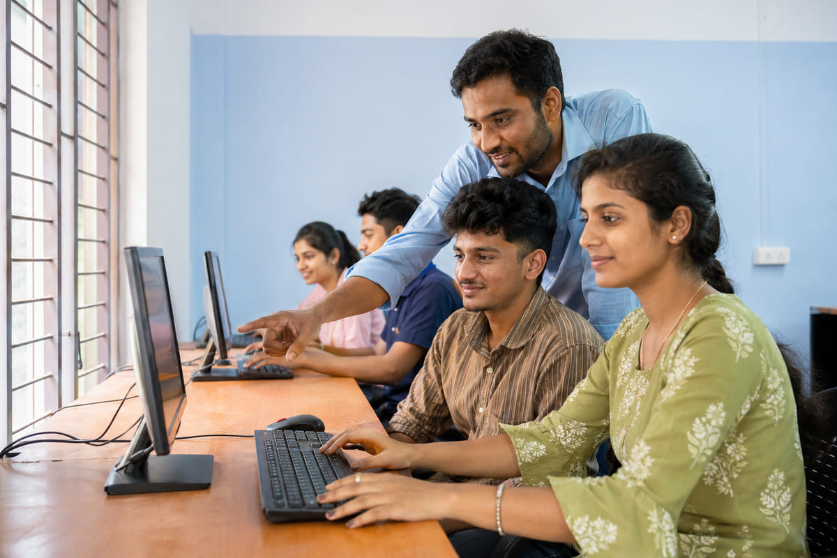 Faculty guiding ADCA diploma students at their computers in the lab at Kundapura